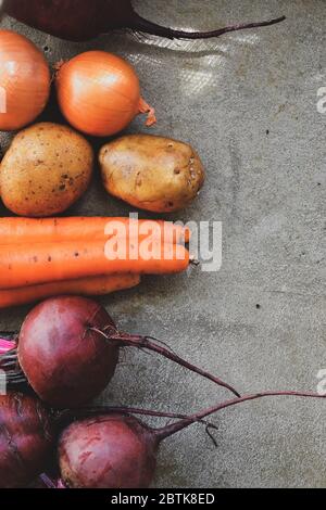 Summer harvest. Beets, potatoes, carrots and onions on a concrete background. Whole raw vegetables, ingredients for soup or borscht. Top view. Free Stock Photo