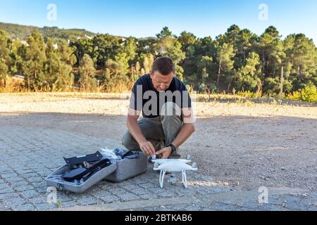 Man, an engineer pilot, prepares air device for take-off, for testing and filming a vileo and photograph. By controlling the remote. Stock Photo