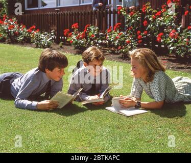 School children lying on grass in school grounds, Surrey, England, United Kingdom Stock Photo