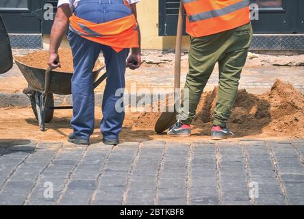 Construction site and two workers on the street doing the renovation Stock Photo