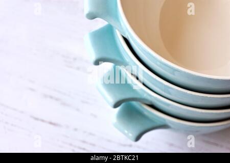 Closeup of a stack of light blue ceramic retro bowls from the 50s on a white painted wooden table with copy space. Stock Photo