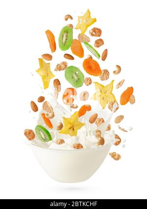 Cereal corn flakes with fruits and nuts falling into the bowl with splashing milk. Isolated on white. Healthy breakfast concept. Stock Photo