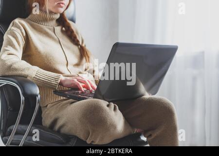 Redheaded woman with laptop working from home, freelance, social distancing and remote work concept. Stock Photo