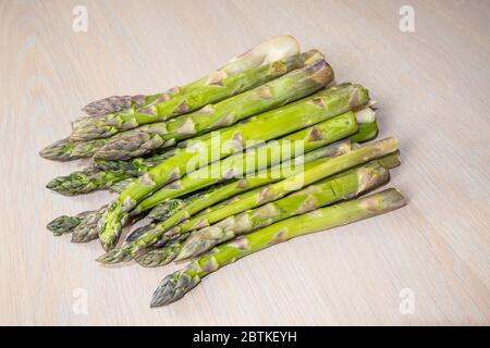 A bundle of cut fresh asparagus (Asparagus officinalis) shoots (spears and tips) on a tabletop in spring Stock Photo