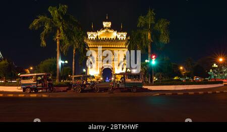 Auto rickshaw in front of Victory Gate Patuxai War Memorial at night  Vientiane Laos Stock Photo