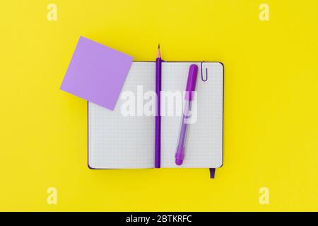 Purple notepad, pencil and marker on a yellow background. Copy space, flat lay. Concept office and back to school. Stock Photo