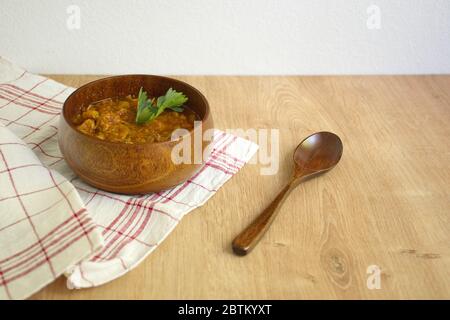 Stew in wooden bowl with wooden spoon on table Stock Photo