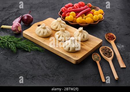 Uncooked khinkali on wooden board with spice and herbs Stock Photo