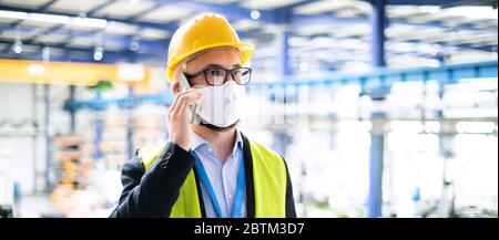 Technician or engineer with protective mask and helmet working in industrial factory. Stock Photo
