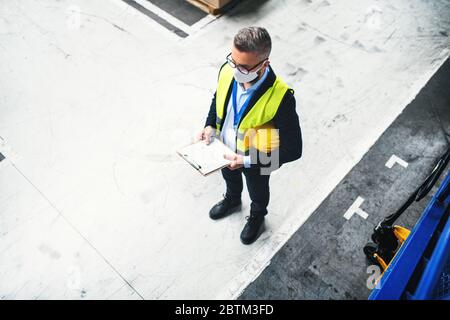 Technician or engineer with protective mask and helmet working in industrial factory. Stock Photo