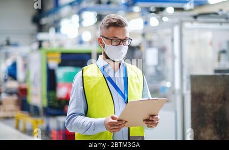 Technician or engineer with protective mask working in industrial factory, walking. Stock Photo