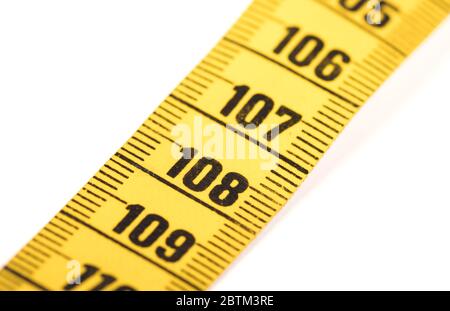 Close-up of a yellow measuring tape isolated on white - 108 - Selective focus Stock Photo