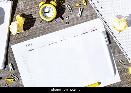 Weekly planner with alarm clock and office supplies. Business planning, workplace Stock Photo