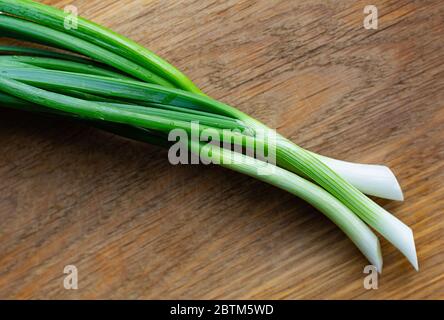 Young green onions on a wooden background. Food and health concept. Copy space. Stock Photo