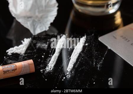 Cocaine lines prepared on a table and a rolled banknote ready to be sniffed Stock Photo