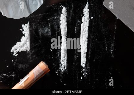 Two Cocaine lines prepared on a table and a rolled banknote ready to be sniffed. Top view Stock Photo