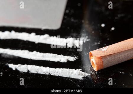 Cocaine lines prepared on a table and a rolled banknote ready to be sniffed Stock Photo