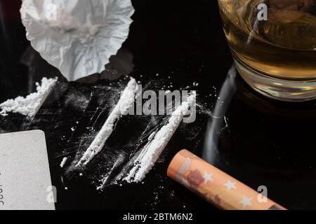 Cocaine lines prepared on a table and a rolled banknote ready to be sniffed Stock Photo