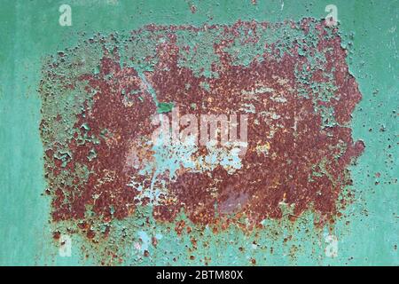 Old green iron sheet with peeling brown paint and rusty spots. Texture paint and rust background for design. Stock Photo