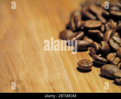 Raw coffee beans close up on a wood chopping board. Stock Photo
