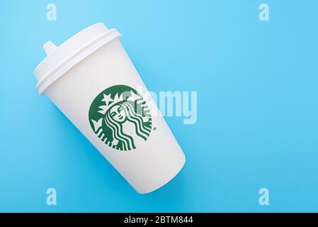 BERLIN - MAY 26: White paper cup with the mermaid as Starbucks logotype on blue background in Berlin on May 26, 2020 in Germany. Stock Photo