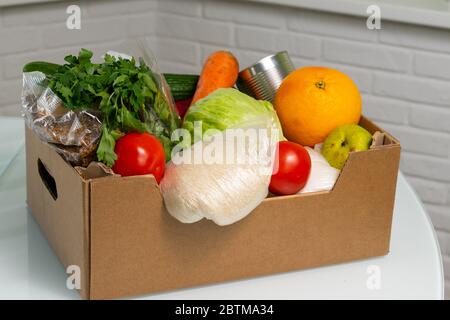 products in a cardboard box are on the kitchen table. food delivery Stock Photo