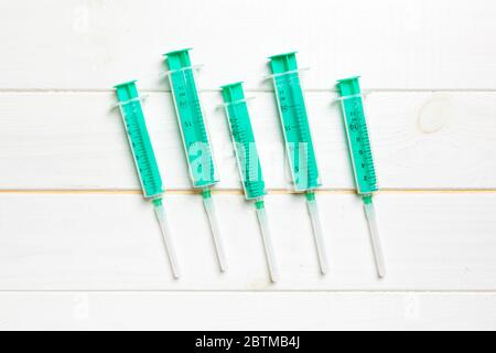 Top view of syringes of different sizes on wooden background. Medical equipment for injection concept with copy space. Stock Photo