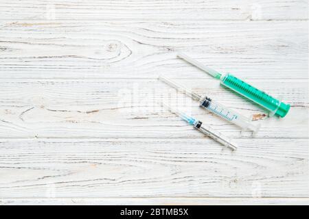 Top view of syringes of different sizes on wooden background. Medical equipment for injection concept with copy space. Stock Photo