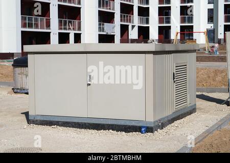 New  modern  small size power electric transformer box installed in the courtyard of an unfinished apartment building for young families Stock Photo