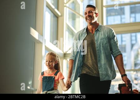 Family of two with their luggage walking through a tunnel for boarding the plane. Father and daughter going on a trip. Stock Photo