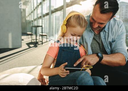 Father and daughter using digital tablet at airport waiting lounge. Family of two at airport departure lounge using tablet computer. Stock Photo