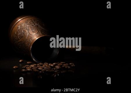 Oriental coffee maker with coffee beans on a black background. Stock Photo