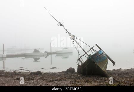 Crosshaven, Cork, Ireland. 27th May, 2020. An old fishing boat lies on its side in front of the marina in Crosshaven, Co. Cork, Ireland. Weather forcast for the day is that coastal fog will clear and become sunny everywhere with tempertures ranging between 20 to 24 degrees celcius.  - Credit; David Creedon / Alamy Live News Stock Photo