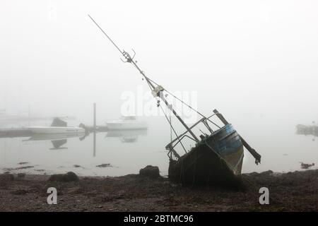 Crosshaven, Cork, Ireland. 27th May, 2020. An old fishing boat lies on its side in front of the marina in Crosshaven, Co. Cork, Ireland. Weather forcast for the day is that coastal fog will clear and become sunny everywhere with tempertures ranging between 20 to 24 degrees celcius.  - Credit; David Creedon / Alamy Live News Stock Photo