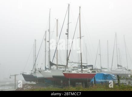 Crosshaven, Cork, Ireland. 27th May, 2020. Heavy fog shrouds yachts at a boatyard in Crosshaven, Co. Cork, Ireland. Weather forcast for the day is that coastal fog will clear and become sunny everywhere with tempertures ranging between 20 to 24 degrees celcius.  - Credit; David Creedon / Alamy Live News Stock Photo