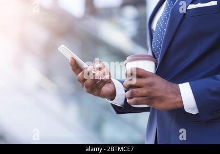Unrecognizable Businessman Texting On Phone Holding Coffee Standing In City Stock Photo