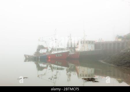 Crosshaven, Cork, Ireland. 27th May, 2020. Fishing boats shrouded in heavy fog at the pier in Crosshaven, Co. Cork, Ireland. Weather forcast for the day is that coastal fog will clear and become sunny everywhere with tempertures ranging between 20 to 24 degrees celcius.  - Credit; David Creedon / Alamy Live News Stock Photo