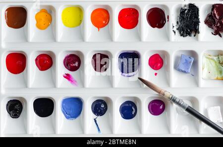 Watercolor paint palette with multicolored bright paints in a plastic container on a light grey background, copy space. Stock Photo