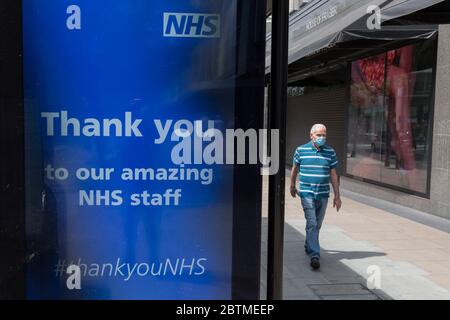 During the UK's Coronavirus pandemic lockdown and in the 24hrs when a further 255 deaths occurred, bringing the official covid deaths to 37,048,  a pedestrian walks past a digital ad thanking NHS staff (National Health Service) at a bus stop on Oxford Street, on 26th May 2020, in London, England. Stock Photo