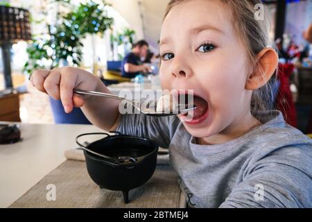 little girl eating dumpling in cafe Stock Photo