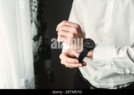 businessman checking time on his wrist watch, man putting clock on hand, groom getting ready in the morning Stock Photo