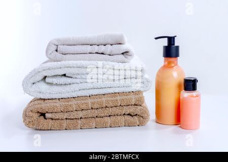 Stack of clean towels with cream and lotion for shower and bathroom treatment. Home spa and relaxation convept on white background Stock Photo