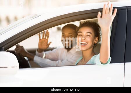 Joyful Couple Waving Hands Sitting In Car Having Road Trip Stock Photo