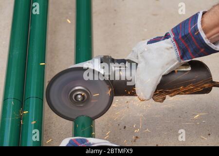 An angle grinder with cutting disc for steel is in use. Cutting steel pipes. Stock Photo