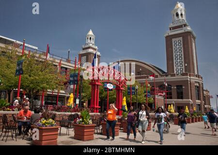 Horizontal shot of four girls passing by the Miller Lite Beer Garden with the Aon Grand Ballroom in the background, Navy Pier on a sunny day, Chicago Stock Photo