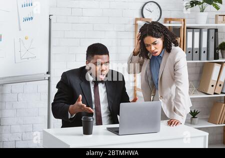 African American colleagues worrying about error in business project, failing to meet deadline at office Stock Photo