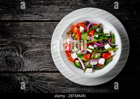 Greek salad with grilled asparagus, cherry tomatoes, cucumbers, black olives, red onion rings with olive oil, soft feta cheese served on a  plate on a Stock Photo