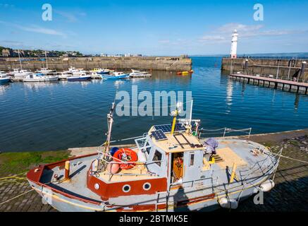 Newhaven, Edinburgh, Scotland, United Kingdom, 27th May 2020. UK Weather: Fishing boats moored in the calm water of the harbour create reflections with one boat on the harbourside Stock Photo