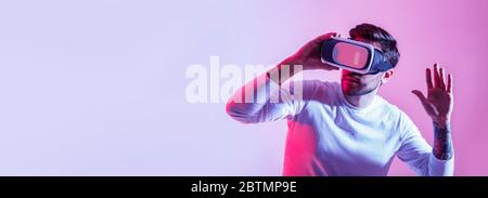 Man impressed with digital world. Guy with virtual reality glasses looks around Stock Photo