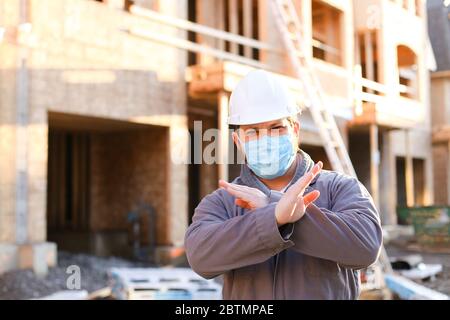 Foreman wearing mask and hardhat at construction site. Stock Photo